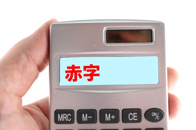 電卓に表示された赤字の文字 電卓を持つ手