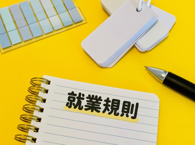 黄色の背景 ノートに書かれた就業規則 単語帳と付箋とペン