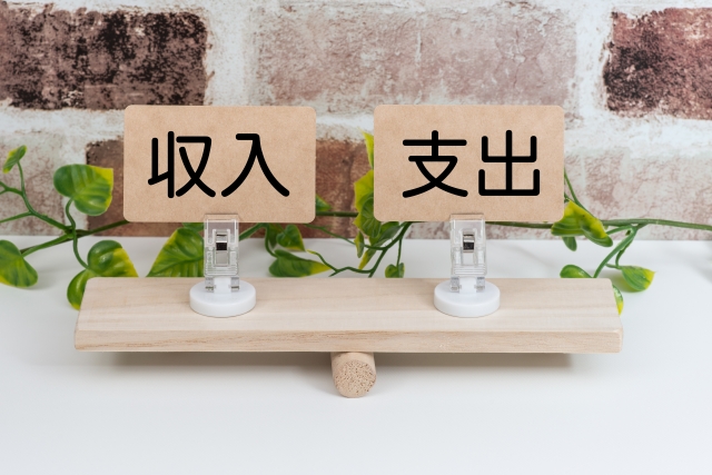 シーソーの上の収入と支出 レンガの壁 ツタ