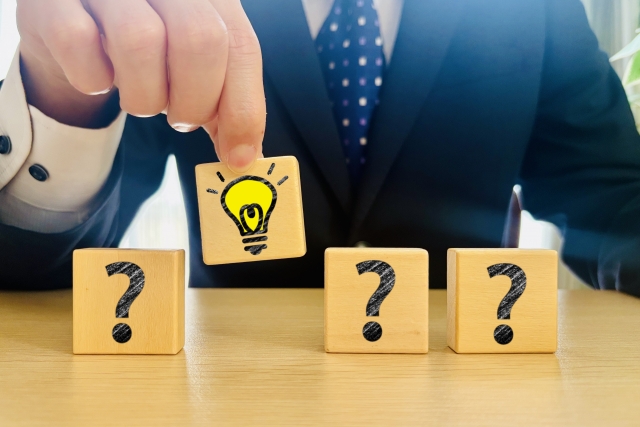 電球マークを摘まむサラリーマン 木のブロック クエスチョンマーク