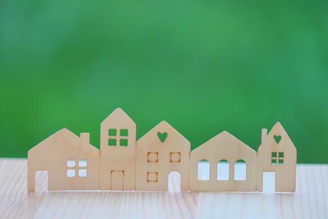 木でできた複数の家の模型 緑色の背景